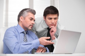 Thoughtful young business man looking at laptop.